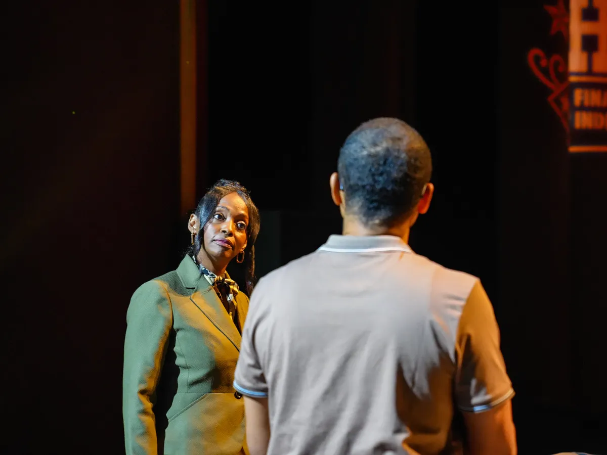 Two people talking on stage under a spotlight