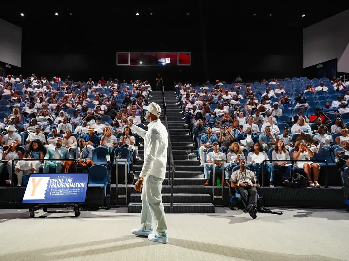 A speaker in white on the floor of a packed auditorium