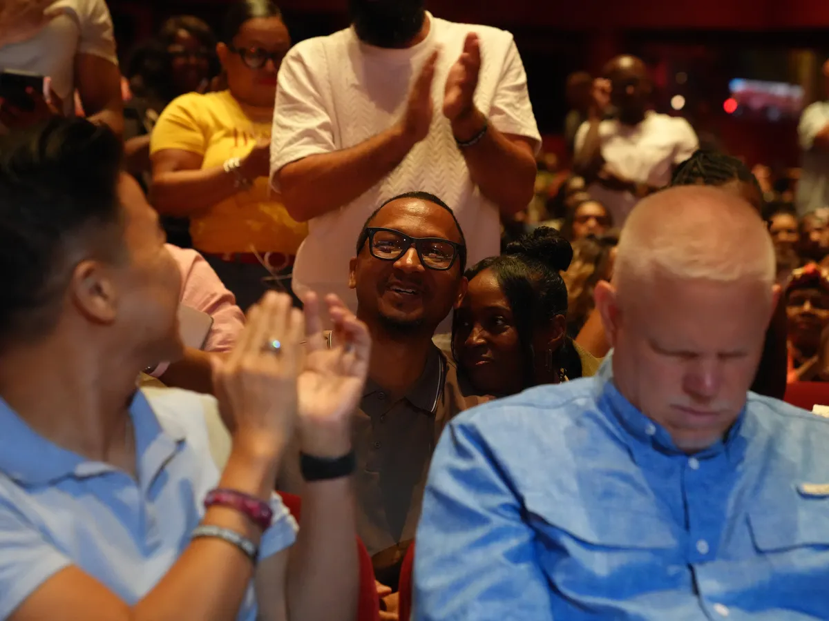 Audience members cheering and applauding from their seats